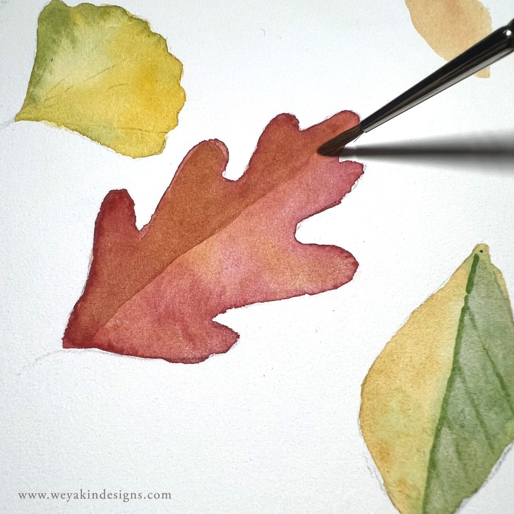 A paintbrush uses watercolors to paint different colored leaves on the page. Art by Victoria K. Chapman.